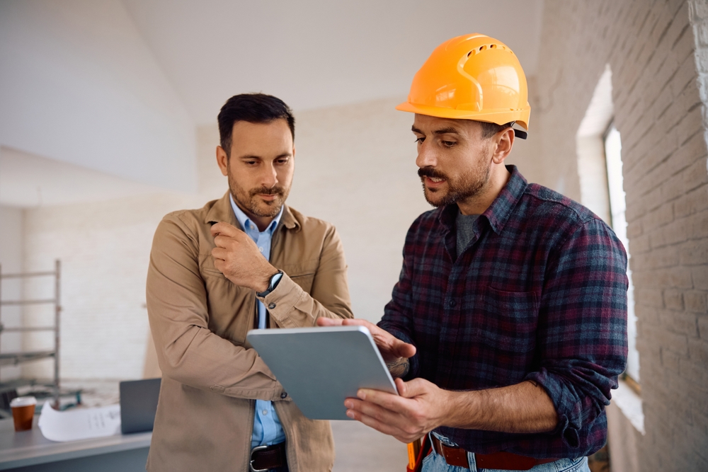 Construction,Worker,Using,Digital,Tablet,With,Home,Owner,During,Renovating